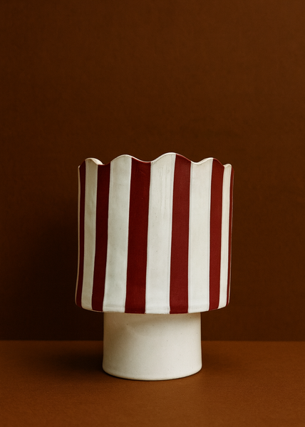 Ceramic vase with red and white striped pattern on a brown background