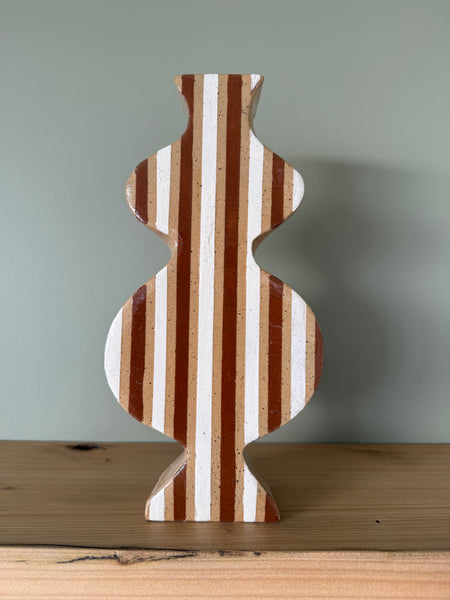 Wooden shelf with a wavy vase on a plain background