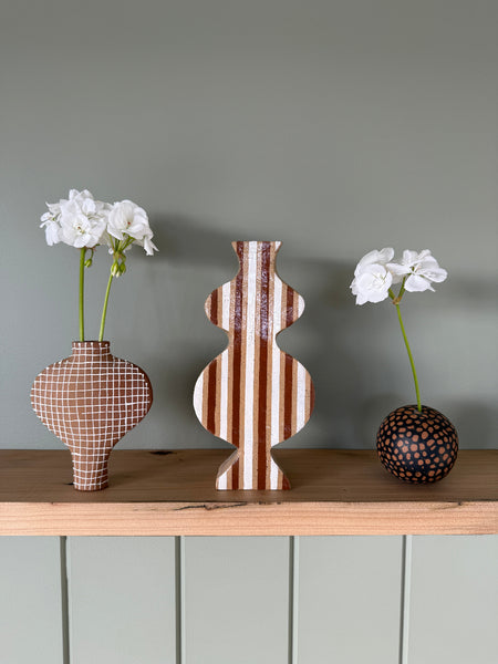 Decorative fish-shaped vase with striped pattern on a green wall