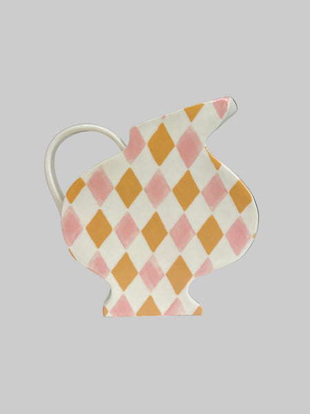 Decorative rabbit-shaped pitcher with pink and yellow diamond pattern on a white surface.