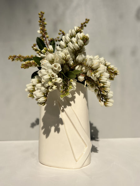 White vase with a bouquet of white flowers on a light gray background