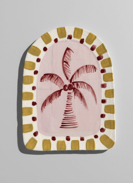 Decorative item with a palm tree design on a pink background, framed by a decorative border.