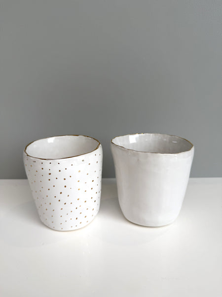 Two ceramic cups on a white surface with a gray background