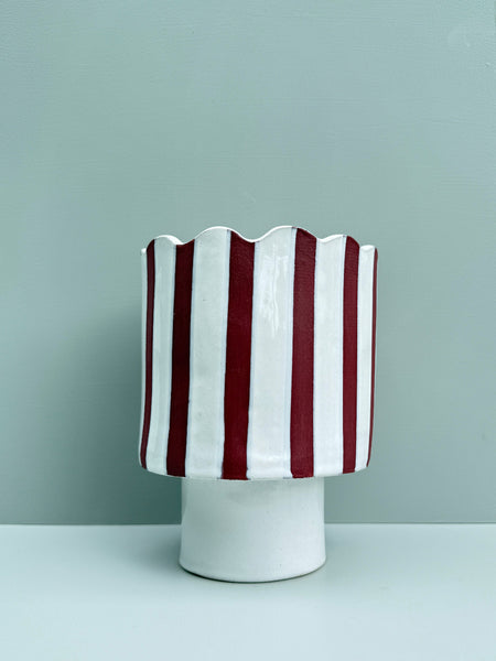 Vase with red and white striped pattern on a light gray background