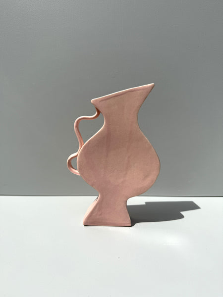 Ceramic pitcher on a white surface with a gray background